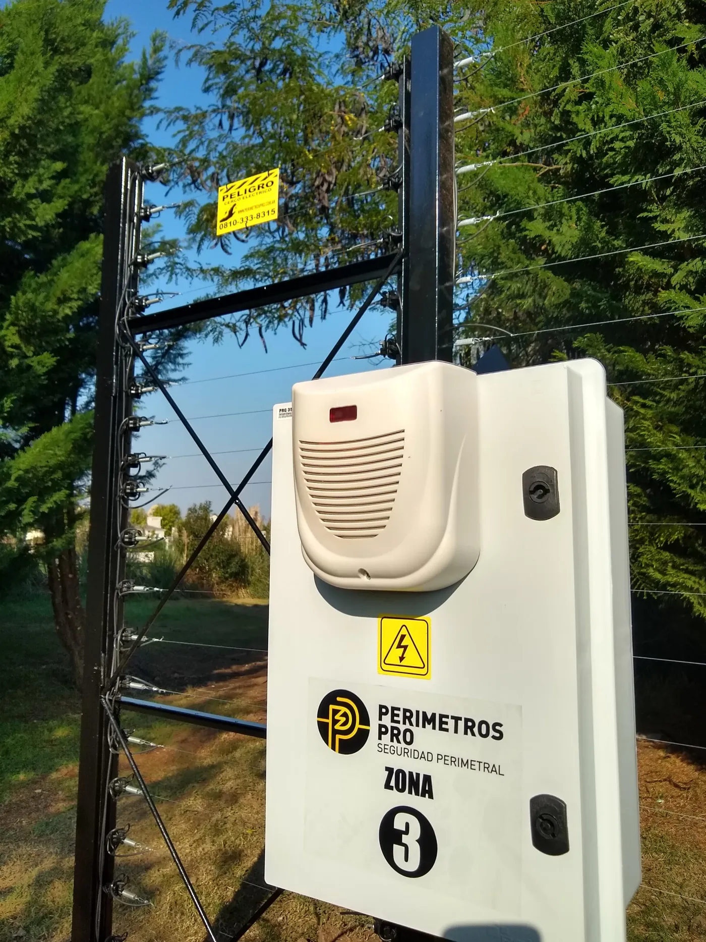Central de cerco eléctrico Perímetros Pro instalada sobre un pórtico autoportante, con sirena y cartelería de zona
