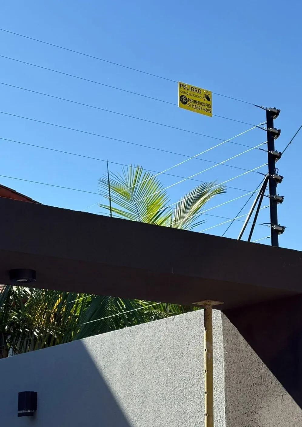 Cerco eléctrico sobre muro de una vivienda, con cartel de Perímetros Pro