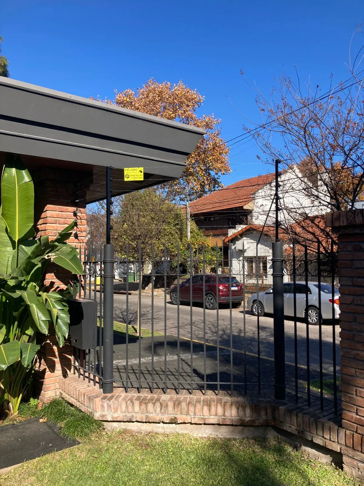 Cerco eléctrico sobre el frente de una vivienda, con calle y acceso