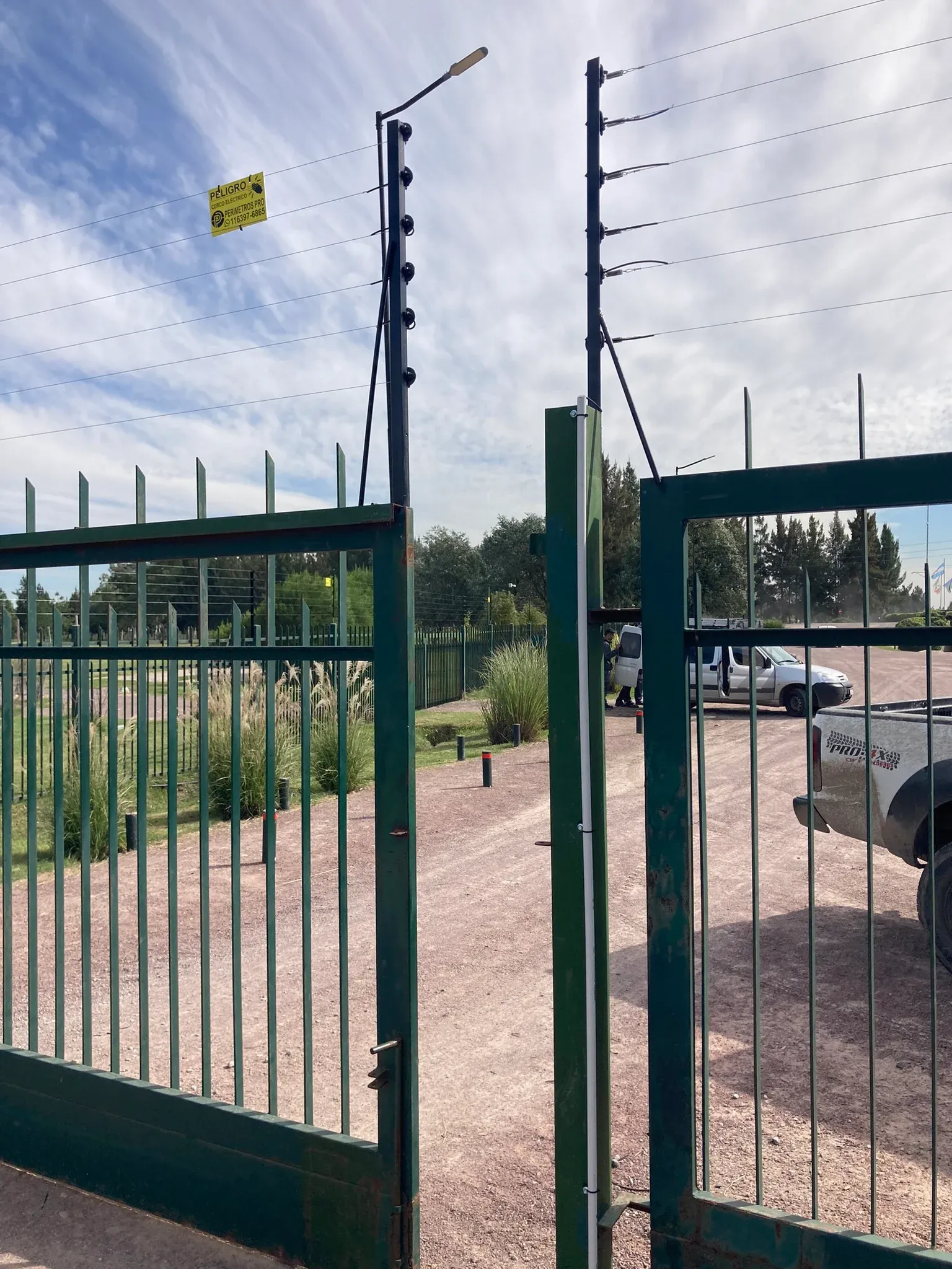 Cerco eléctrico en el acceso de un barrio, con portón y cámara