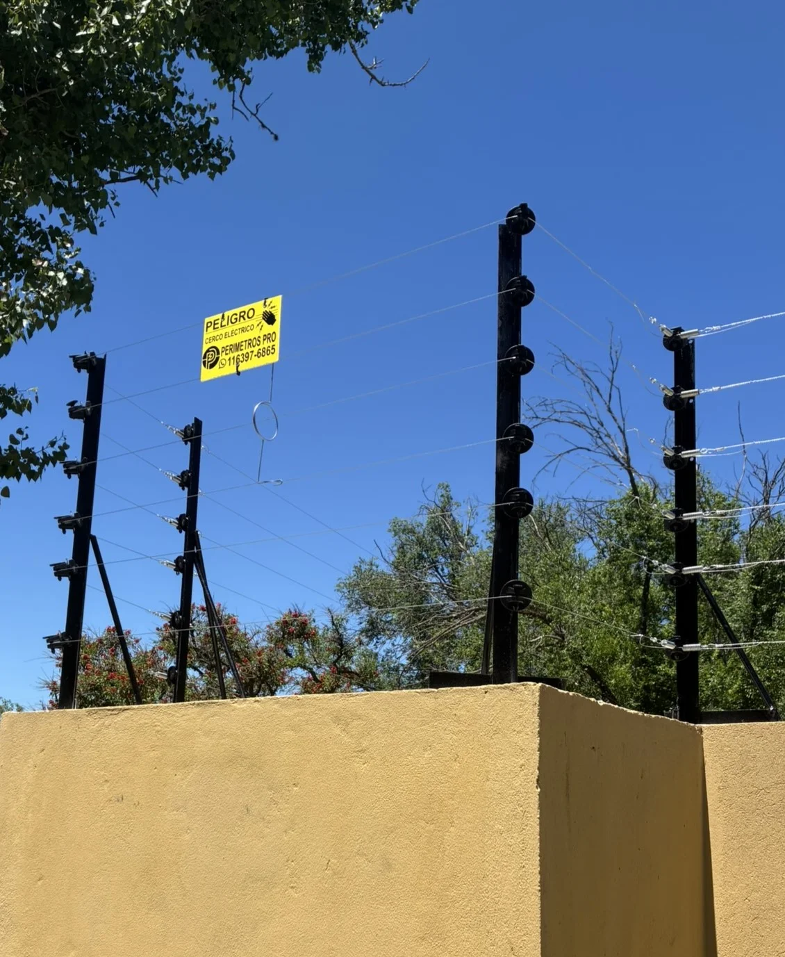 Cerco eléctrico de Perímetros Pro montado sobre muro, con cartel de peligro